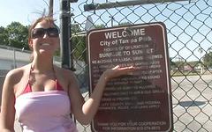 Cheeky brunette walks through a public park in daylight flashing the camera join background